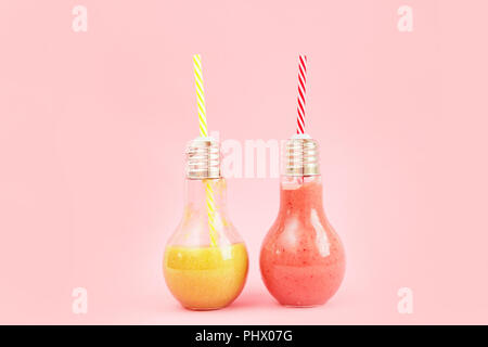 Deux pots en forme de lampe avec smoothies aux fruits isolé sur fond rose. Banque D'Images