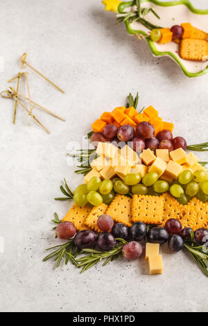 Arbre de Noël de l'entrée : le fromage, les raisins, les craquelins. Concept de nourriture de Noël, fond blanc. Banque D'Images