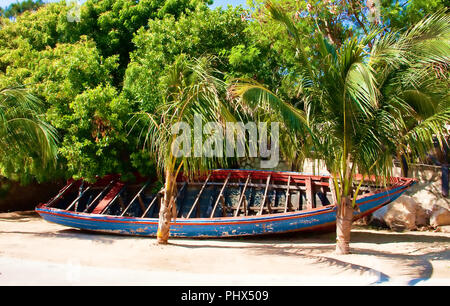 Une vieille barque en bois sous les palmiers sur une plage tropicale Banque D'Images