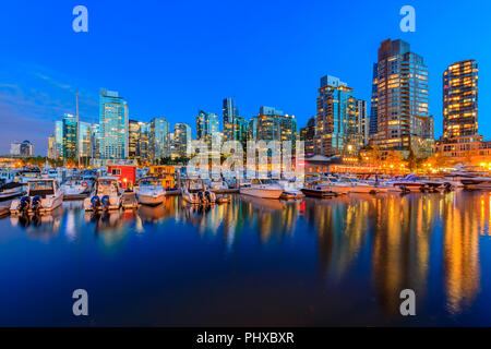 Août 04, 2018 - Vancouver, Canada : le coucher du soleil à Coal Harbour avec des édifices du centre-ville, des bateaux et des reflets dans l'eau Banque D'Images