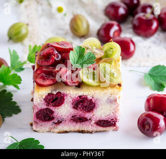 Morceau de gâteau à base de fromage cottage, de cerises et de groseilles sur un tableau blanc, Banque D'Images