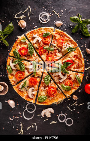 Mise à plat avec pizza italienne sur fond noir et divers ingrédients Banque D'Images