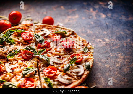 Italian pizza garnie de champignons, fromage, tomate et basilic Banque D'Images