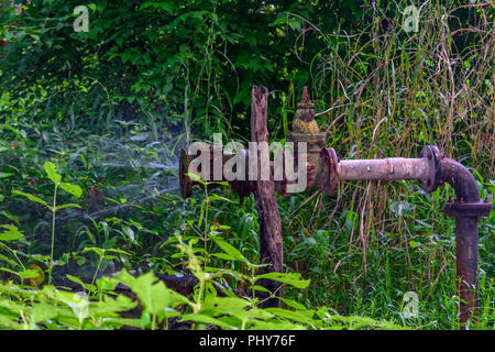 Ancien fer à repasser de canalisation d'eau qui fuit. L'éclatement d'un tuyau rouillé pulvériser de l'eau. Banque D'Images