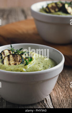 Potage à la courgette en bonne santé dans des bols en céramique sur table en bois Banque D'Images