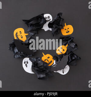 Cadre décoratif de round battant blanc flottant esprit fantômes et citrouilles jaune souriant, chauves-souris noire sur un fond de papier noir. Banque D'Images