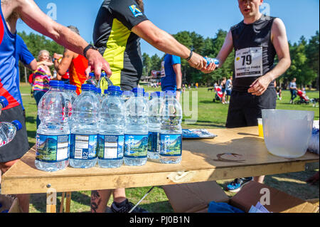 L'eau en bouteille en plastique d'être remis aux coureurs à l'arrivée sur les 2018 Sherwood Pines 10k. Banque D'Images