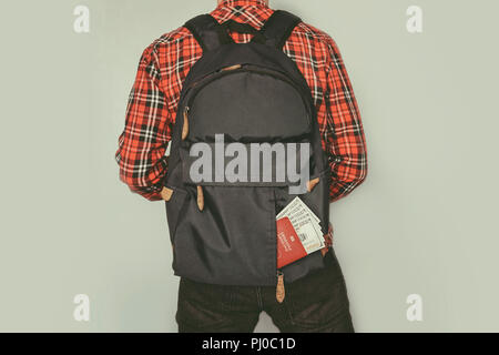 Un homme avec un petit sac à dos tenant la ceinture. L'homme voyageur confiant. passeport montrant dans une poche arrière de jeans. les dépenses en voyages touristiques. main Lugga Banque D'Images