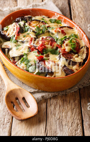 Recette d'été pour l'aubergine en cocotte avec tomates, herbes et fromage close-up dans un plat allant au four, sur une table verticale. Banque D'Images