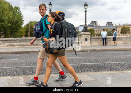 Woman femme à côté de lui pendant qu'elles marchent le long d'un pavé parisien transportant des sacs à dos Banque D'Images