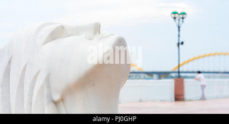 Da Nang Riverside : une sculpture en marbre de la tête d'une femme qui se tourne vers le ciel et, dans l'arrière-plan flou, l'homme se pencha sur la rampe par un éclairage de rue Banque D'Images