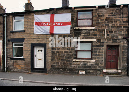 Très grand St George's flag fixé au mur avant d'une rangée de maisons mitoyennes à Manchester Banque D'Images