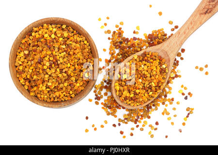 Bee pollen frais dans un bol et cuillère en bois isolé sur fond blanc. Vue d'en haut. Mise à plat. Banque D'Images