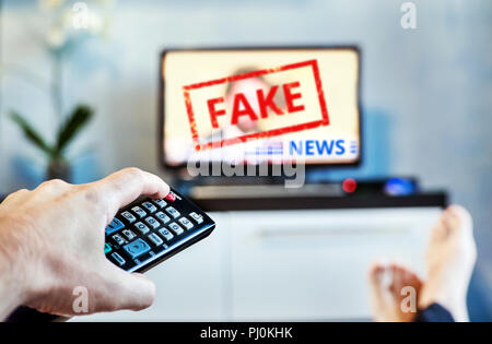 Fake News canular de propagande télévision Politique Sociale Internet. Jeune homme regardant le faux reportage sur la TV à la maison. L'agitation et de la propagande dans le moderne Banque D'Images