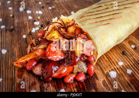 Shaurma. Un plat traditionnel tourbillonné dans du pain pita avec des ingrédients de tranches de pommes de terre et haricots saucisses. Banque D'Images