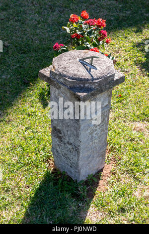 Un cadran solaire sur un socle en béton dans un jardin de fleurs Banque D'Images