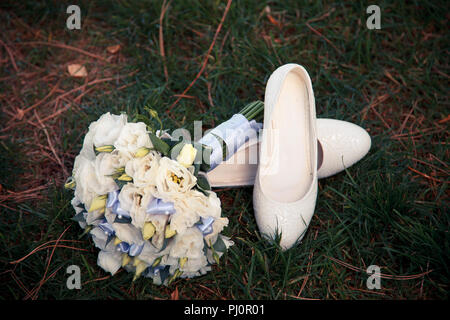 Beau bouquet de mariée mariage avec chaussures de mariage sur fond d'herbe verte. La composition floristique, set de mariee Banque D'Images