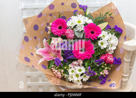 Bouquet de lys rose et rose gerbera enveloppé dans du papier à motifs Banque D'Images