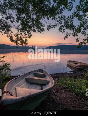 Vue panoramique sur le coucher du soleil avec deux chaloupe et lac idyllique à une nuit d'été en Finlande Banque D'Images