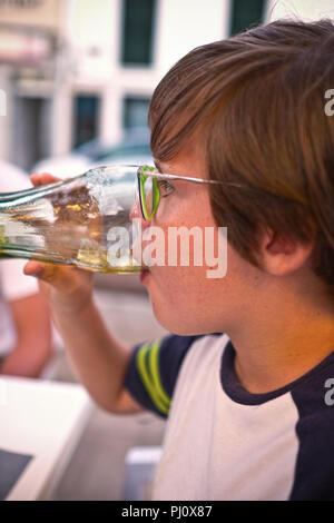 Close up portrait de garçon de onze ans avec des verres d'alcool dans un verre sur une terrasse dans un café en Espagne Banque D'Images