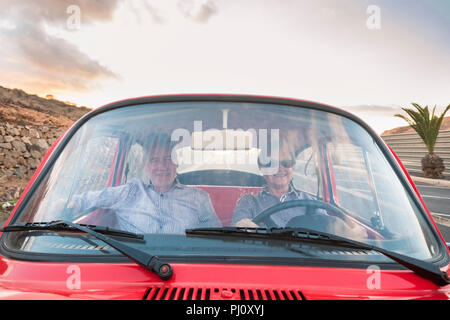 Joli couple dur et de l'amour à l'intérieur d'un vieux millésime rouge voiture garée sur la route. sourit et s'amuser voyageant ensemble. Le bonheur et le mode de vie pour Banque D'Images
