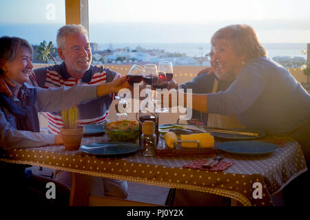 Deux groupes de personnes adultes senior Hommes et femmes s'amusant eatgin ensemble sur la terrasse du toit de la maison. soir Temps de célébration pour les personnes âgées Banque D'Images