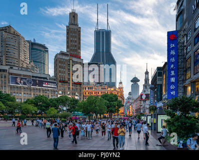 Une foule de promenades à travers la Place du Peuple à Shanghai en Chine, alors que le soleil se couche sur une belle journée d'été. Banque D'Images