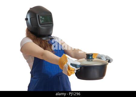 La fille en vêtements de travail et un masque de soudage est titulaire d'une casserole en main tendue vers l'avant. Banque D'Images