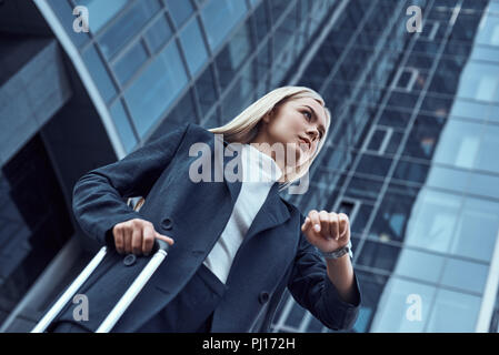 Femme regardant sa montre-bracelet en allant à l'office de consultation sur l'arrière-plan de la ville Banque D'Images