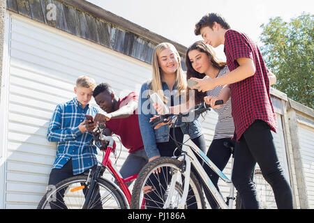 Groupe d'amis adolescents sur des vélos à la recherche de téléphones mobiles Banque D'Images