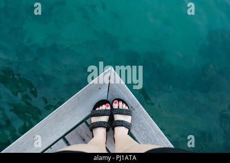 Close-up of a woman's pieds debout sur le bord d'une jetée en bois, Tahiti, Polynésie Française Banque D'Images