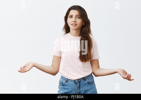 Portrait de femme nerveux ne peut pas décider quoi faire en haussant les mains avec propagation de côté étant pas sûr ou incertain quel choix sera juste position confus sur fond gris Banque D'Images