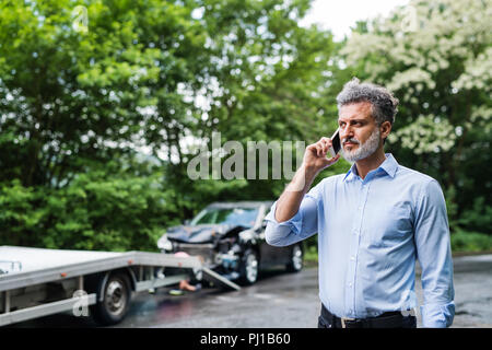 Young man making a phone call après un accident de voiture. Copier l'espace. Banque D'Images