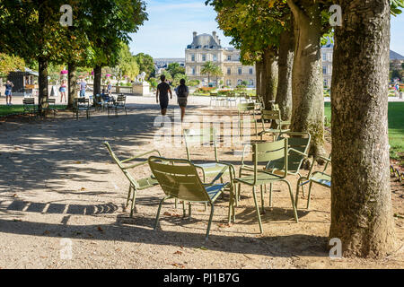 Les gens se promener ou se reposer sur des chaises dans le jardin du Luxembourg à Paris, France, par un matin ensoleillé avec le palais du Luxembourg dans l'arrière-plan. Banque D'Images