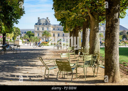 Les gens autour, se promener ou se reposer sur des chaises de métal dans le jardin du Luxembourg à Paris, France, avec le palais du Luxembourg dans l'arrière-plan. Banque D'Images