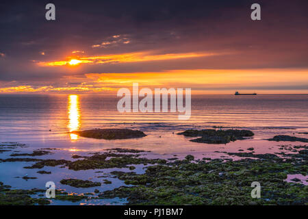 Le soleil se lève sur une mer calme à Roker à Sunderland. Banque D'Images