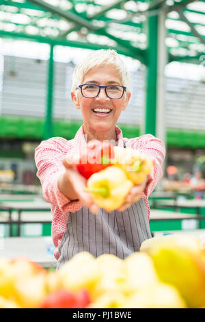 Portrait of senior woman vend des légumes bio sur le marché intérieur Banque D'Images