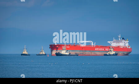 La puissance de la mer Égée pétroliers d'un port en lourd de 115 754 tonnes est amené dans le port des sables bitumineux d'étanchéité par quatre remorqueurs. Banque D'Images