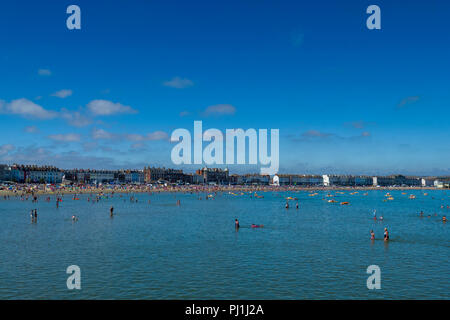 Les gens se détendre et de prendre part à des activités de l'eau sur les eaux peu profondes de la baie de Weymouth par plage de Weymouth, Dorset, England, UK Banque D'Images