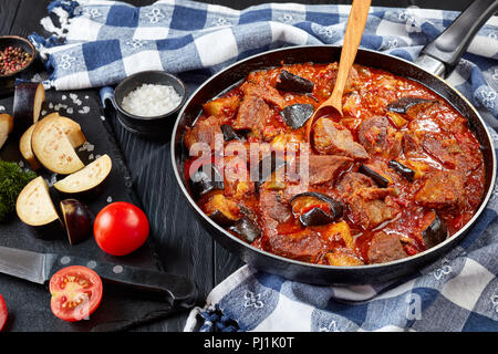 Ragoût de boeuf Aubergine - Khoresht Bademjan dans une poêle sur une table en bois noir avec une serviette de cuisine et les ingrédients, persian cuisine, vue de dessus, clo Banque D'Images