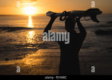 Surfer carrying surfboard sur sa tête le Banque D'Images