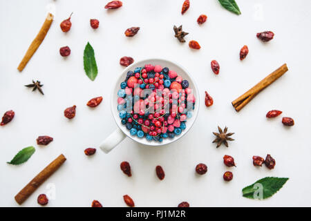 Petits fruits différents dans une tasse sur un arrière-plan blanc joliment décorées. Banque D'Images