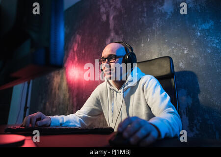 La technologie, jeux, animation, let's play et personnes concept - heureux jeune homme à lunettes avec casque jouant et gagnant le jeu de l'ordinateur à la maison et de streaming vidéo walkthrough playthrough ou Banque D'Images