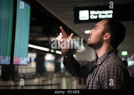 L'homme en face des Arrivées et départs à l'aéroport. Concept de voyage Banque D'Images