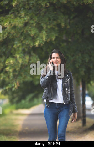 Woman talking on mobile phone mobile tout en marchant dans la rue Banque D'Images