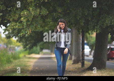 Woman talking on mobile phone mobile tout en marchant dans la rue Banque D'Images