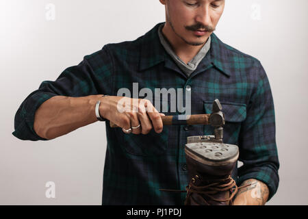 Portrait d'un cordonnier mesurant une chaussure avec ruban de mesure en atelier Banque D'Images