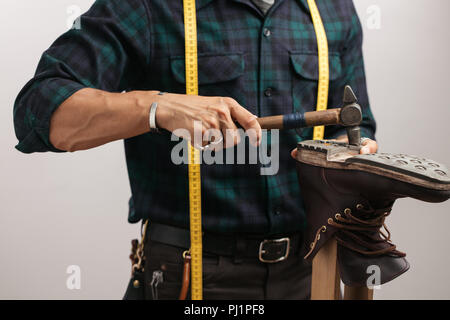 Portrait d'un cordonnier mesurant une chaussure avec ruban de mesure en atelier Banque D'Images