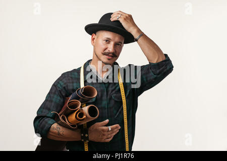 Artisan du cuir dans creative black hat posing with maroquinerie en studio. Banque D'Images