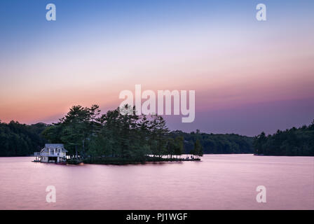 Un petit chalet au bord du lac sur une île dans le Muskoka, Ontario, au lever du soleil. Banque D'Images